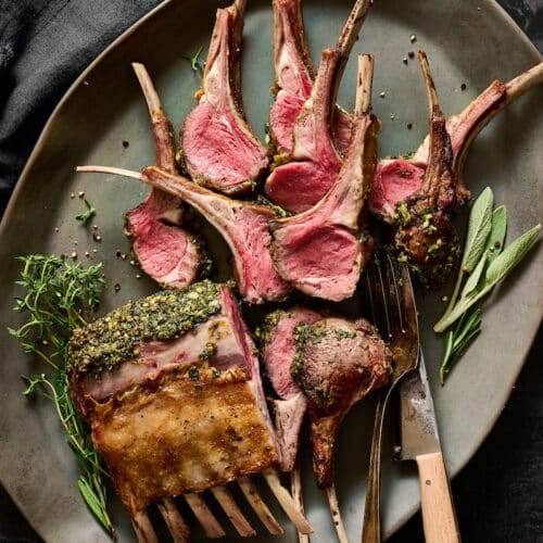 Black plate with rack of lamb cut into lamb chops.